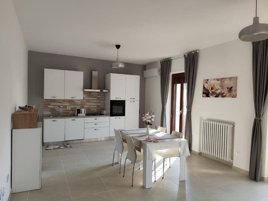 a kitchen and dining room with a white table and chairs at Casa Vacanza Magnolia in Tollo