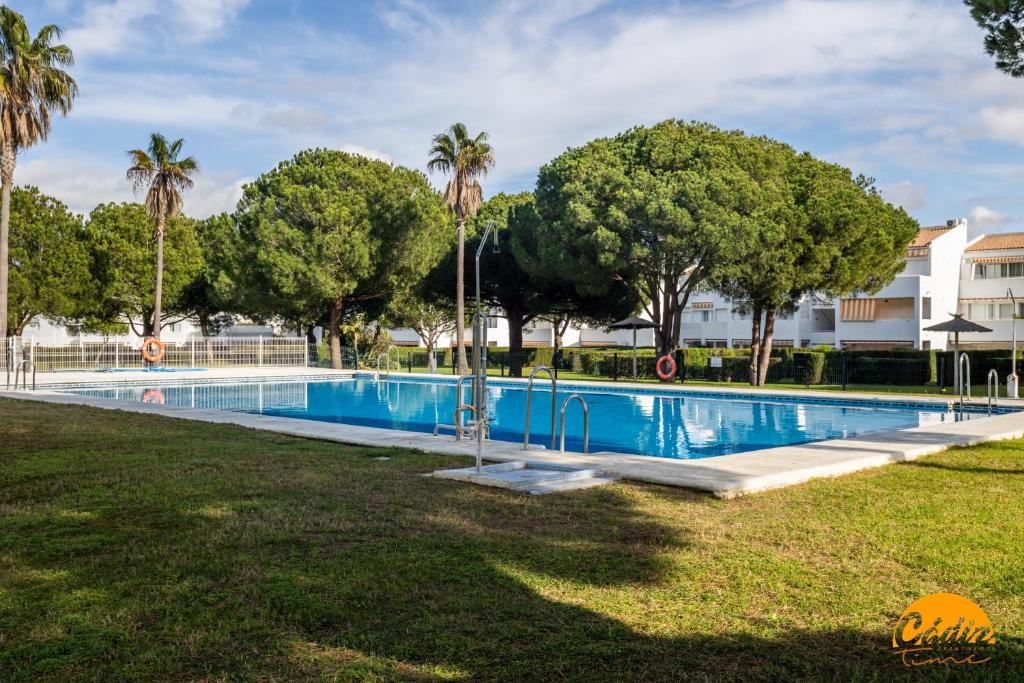 a swimming pool in a park with palm trees at Retama Golf by Cadiz Time in Novo Sancti Petri