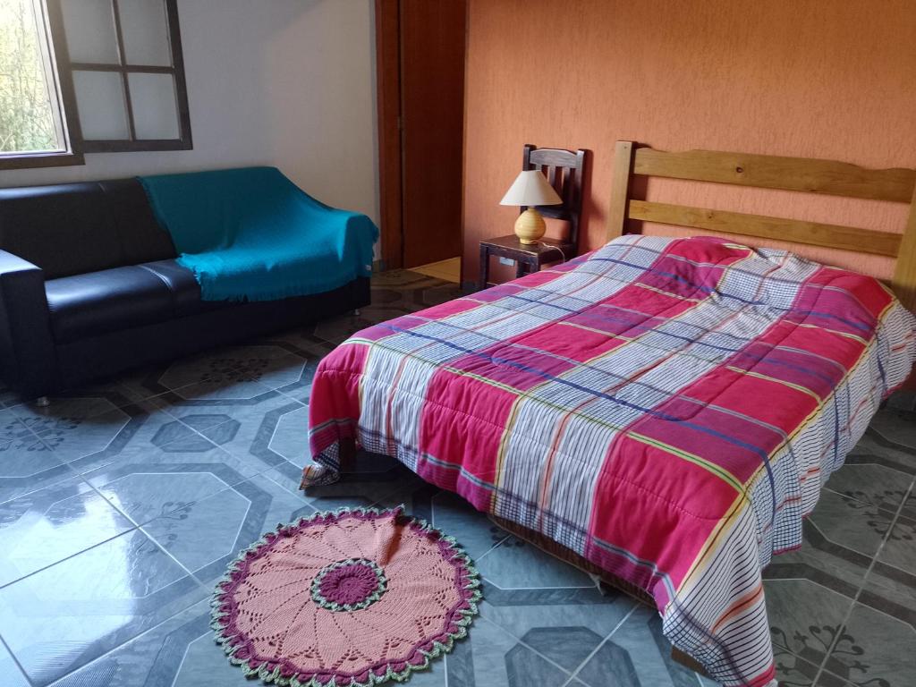 una camera da letto con un letto e un divano di Casa de Campo - Vista Exuberante São Bento do Sapucaí a São Bento do Sapucaí