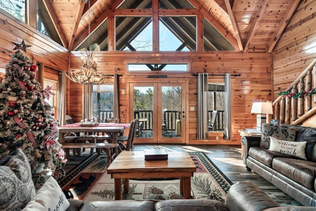 a living room with a christmas tree in a log cabin at 8 Beds, Hot Tub, Fireplaces, Pool Tbl Arcade VIEWS! in Sevierville