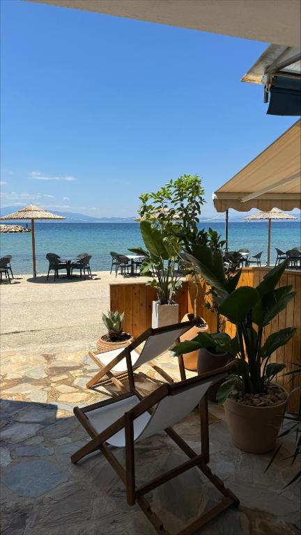 a beach with a chair and tables and the ocean at Casa Del Mar Thassos in Skala Sotiros