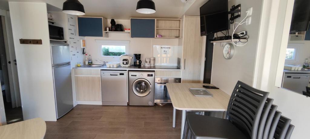 une cuisine avec une table et une machine à laver dans l'établissement mobilhome Samba 3 chambres, aux Mathes