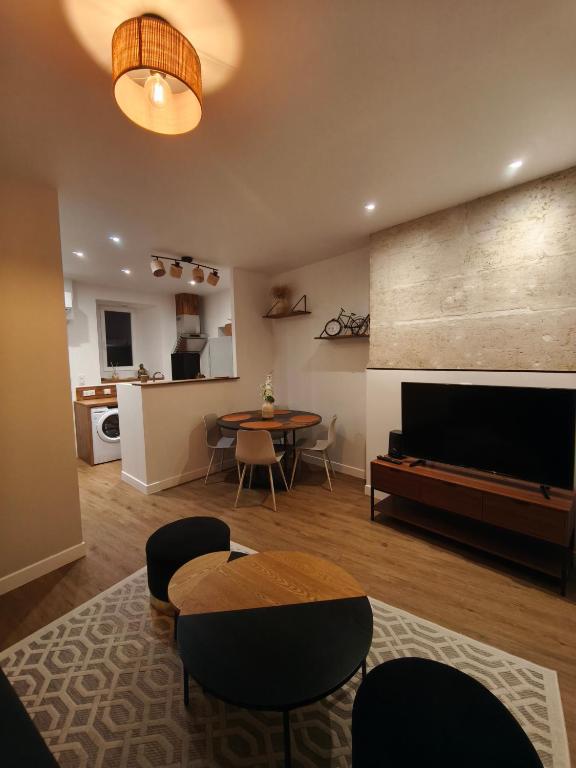 un salon avec une télévision, une table et des chaises dans l'établissement Appartement centre ville historique avec terrasse et climatise, à Périgueux