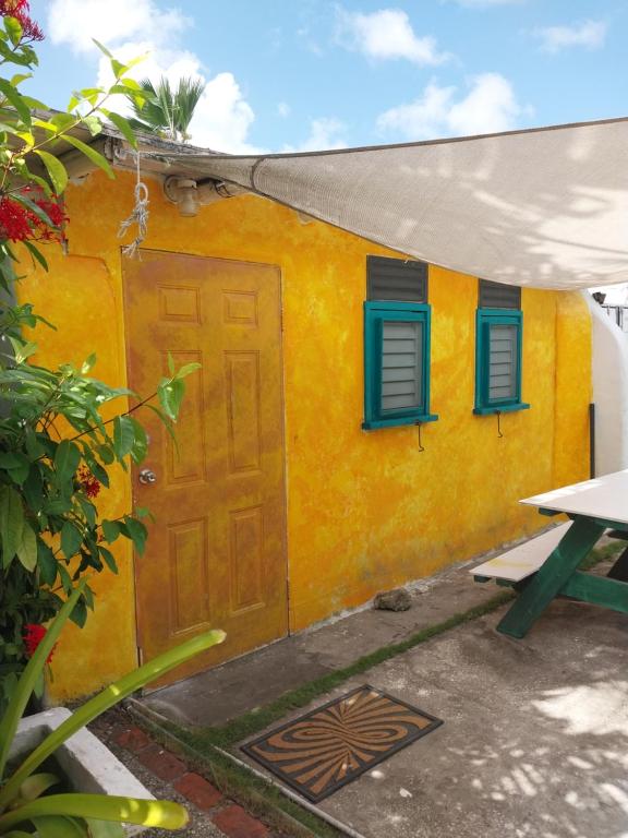 ein gelbes Haus mit blauen Fenstern und einer Tür in der Unterkunft SHAMBHALA Homestays Cottage and Studio in Christchurch