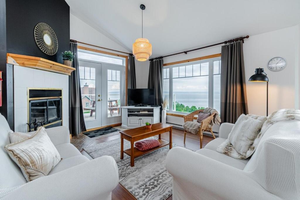 a living room with two white chairs and a fireplace at Panoramic view 2CH Fireplace BBQ Terrace - High Unit in Petite-Rivière-Saint-François