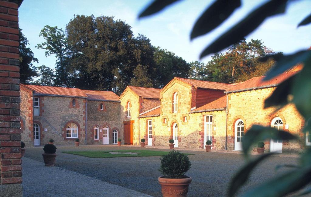 ein großes Backsteingebäude mit Bäumen im Hintergrund in der Unterkunft B&B Domaine de La Corbe in Bournezeau