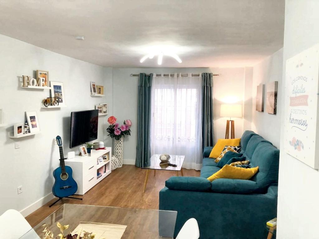 een woonkamer met een blauwe bank en een tv bij Comfortable house in Fuengirola with terrace in Fuengirola