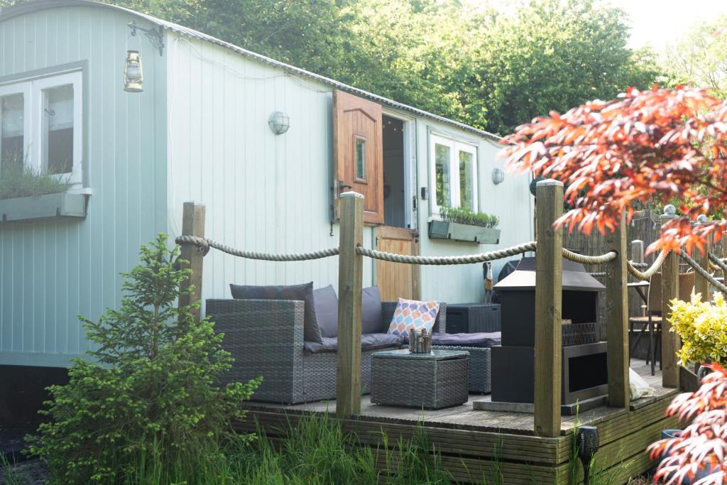 リミントンにあるShepherds Hut with Hot Tubのソファ付きのパティオ、家