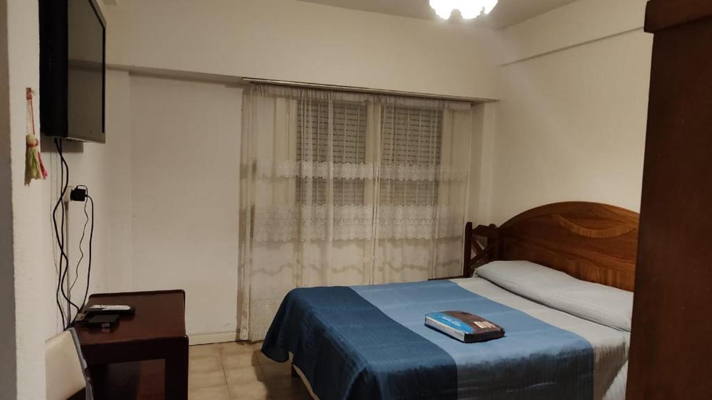 a bedroom with a bed with a blue blanket and a window at La calida in Mar del Plata