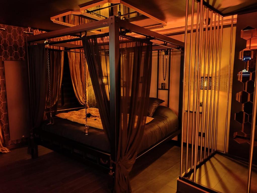 a bed in a room with a canopy bed with curtains at Appartement LOVE ROOM LUXE in Bavay