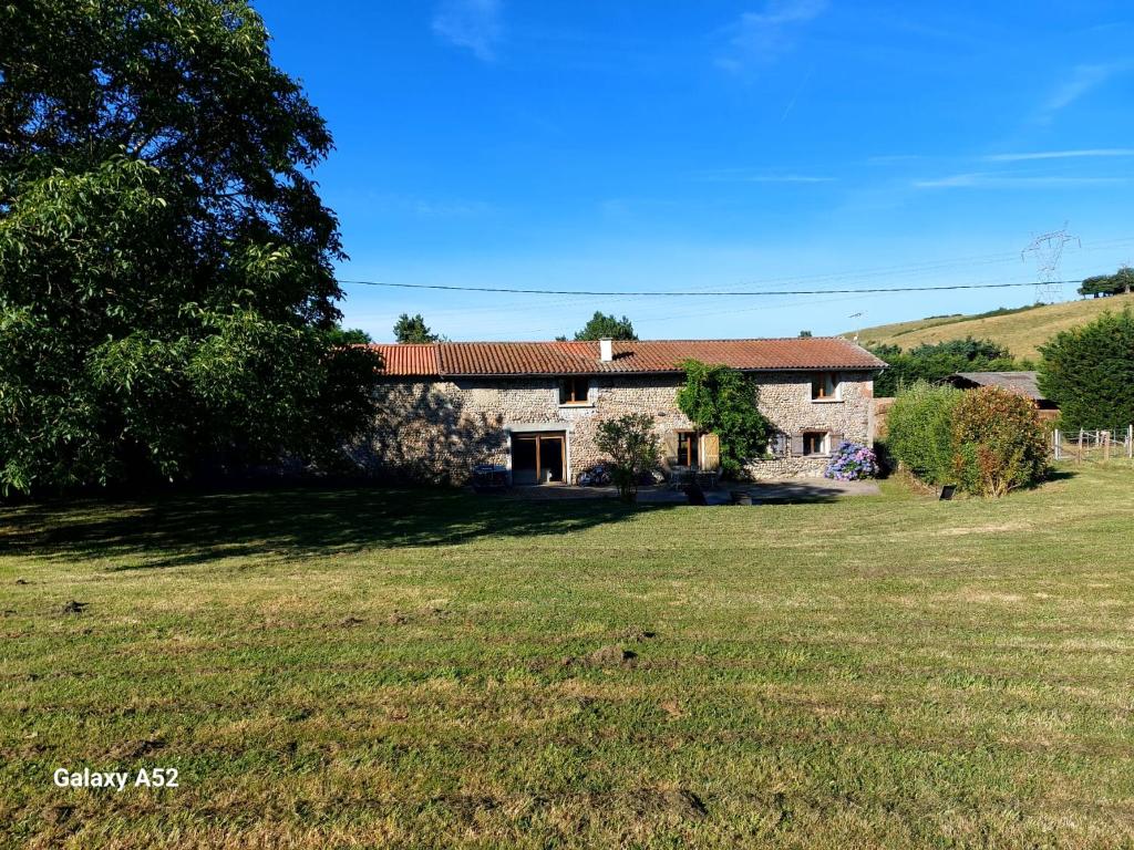 une maison en pierre avec une grande pelouse devant elle dans l'établissement Les coqs de Mirebois ,Maison de campagne de 200 M2 pour 10 Personnes, à Bas-Mollard