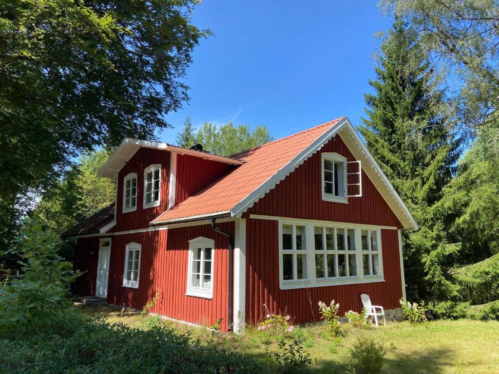 a red house with a white window and a chair at Torsholma Skolhus in Hallaryd