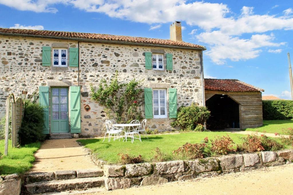 une vieille maison en pierre avec une table et des chaises dans la cour dans l'établissement Maison accueillante avec vue sur le lac à Moncoutant, à Moncoutant