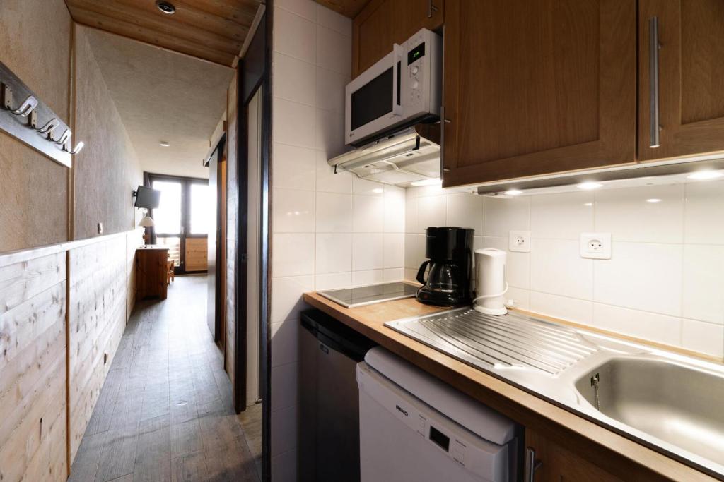 une petite cuisine avec un évier et un micro-ondes dans l'établissement Résidence Etoile - Studio pour 4 Personnes 094, à Aime La Plagne