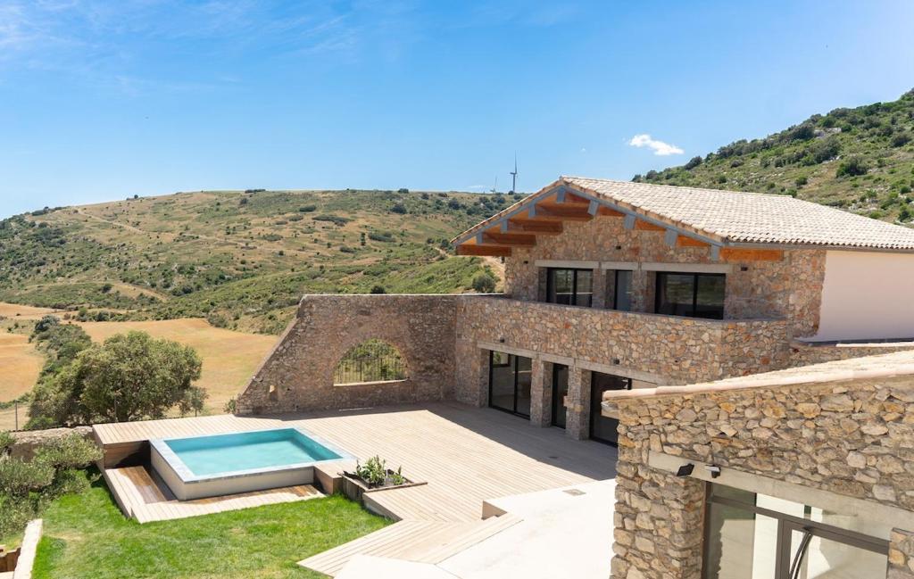 une maison en pierre avec une piscine dans la cour dans l'établissement La Villa du Mas d 'Antonegre, à Montbazin
