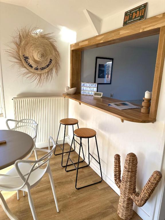 a kitchen with a counter and chairs and a table at Little Omaha in Vierville-sur-Mer
