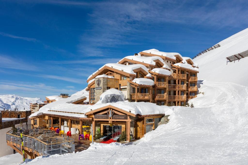 um edifício coberto de neve no topo de uma montanha em Hotel Pashmina Le Refuge em Val Thorens