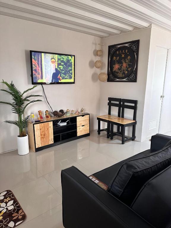a living room with a couch and a tv on the wall at Casa de Ligaya San Pablo in San Pablo