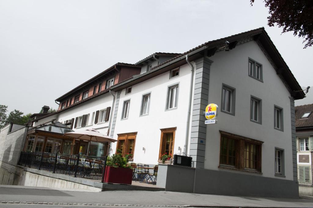 un bâtiment blanc avec un panneau devant lui dans l'établissement Hirschen B&B, à Maienfeld