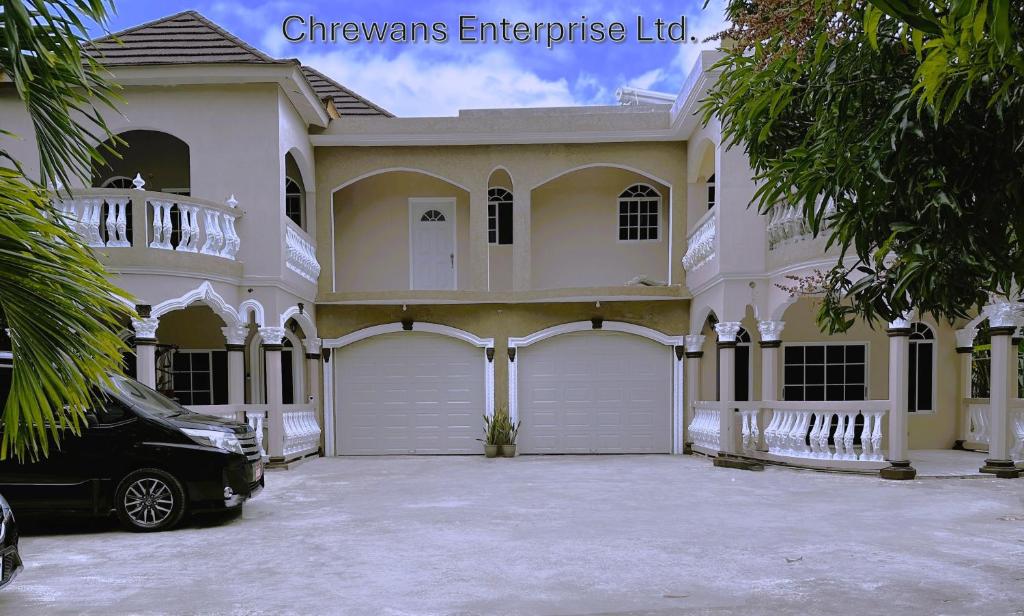 una casa bianca con una macchina parcheggiata di fronte di Chrewans Enterprise Ltd a Montego Bay