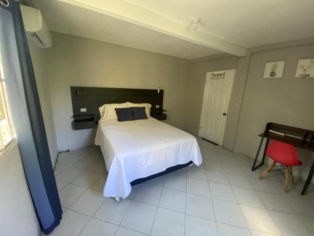 Un dormitorio con una cama blanca y una silla roja. en Habitación cerca del aeropuerto #1, en Tilapa
