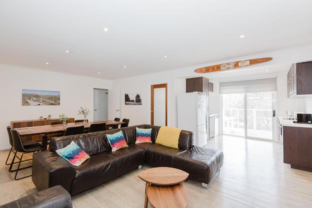 a living room with a brown leather couch and a kitchen at 46 Banjo Patterson Crescent in Jindabyne