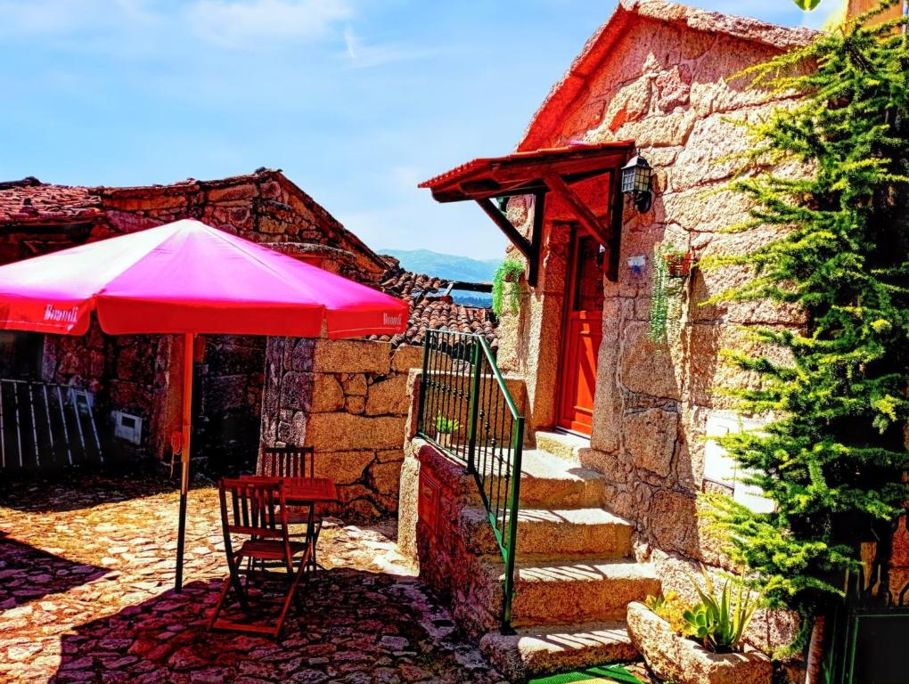 einem roten Regenschirm und einem Tisch und Stühlen vor einem Haus in der Unterkunft Comfortable house in Lindoso, stunning mountain view in Pedras de Moledo
