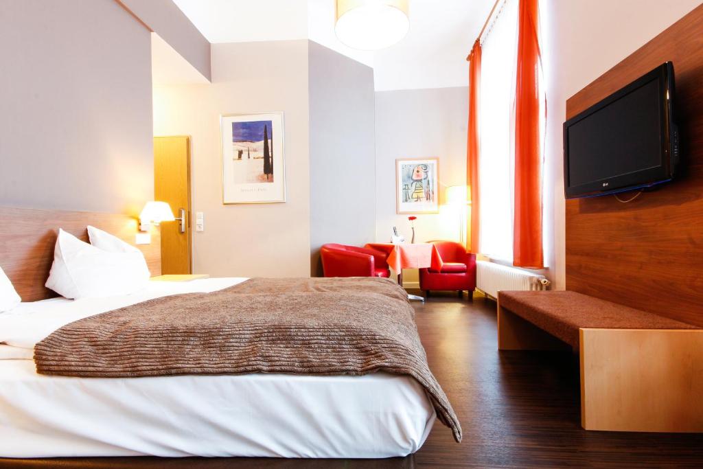 カールスルーエにあるHotel am Tiergartenのベッド1台、薄型テレビが備わるホテルルームです。