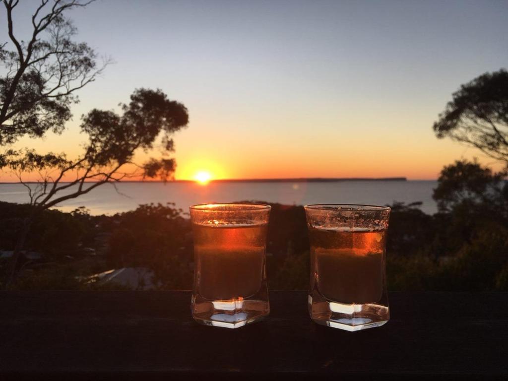 due bicchieri di birra con il tramonto sullo sfondo di Hawkesview a Vincentia