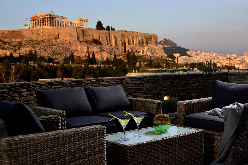 eine Terrasse mit einem Sofa und einem Tisch mit Weingläsern in der Unterkunft KARYATIS LUXURY MAISONETTE by K&K in Athen