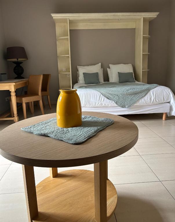 - une chambre avec un lit et une table avec un vase jaune dans l'établissement Suite Supérieure 40 m2 Domaine du Golf St Endreol, 1 à 4 personnes, à La Motte