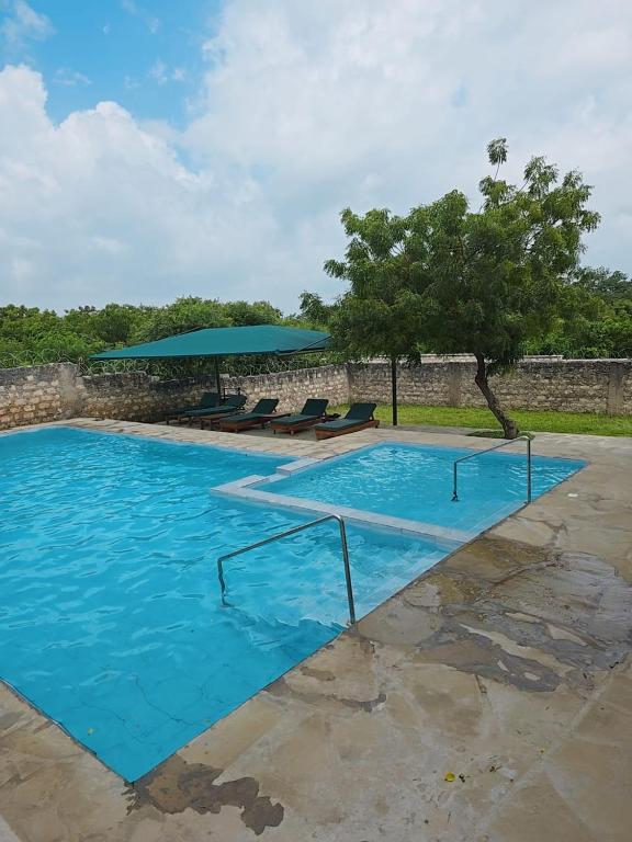 a large blue swimming pool with a umbrella and chairs at Jade luxury Apartments in Galu