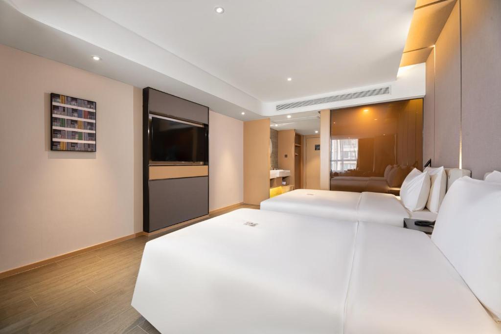 a hotel room with two beds and a flat screen tv at Atour Hotel Xi'an Gaoxin North Zhangba Road in Xi'an