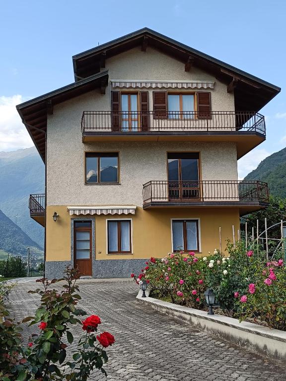 a house with a balcony and flowers in front of it at Casa vacanze Orobie in Villa di Tirano