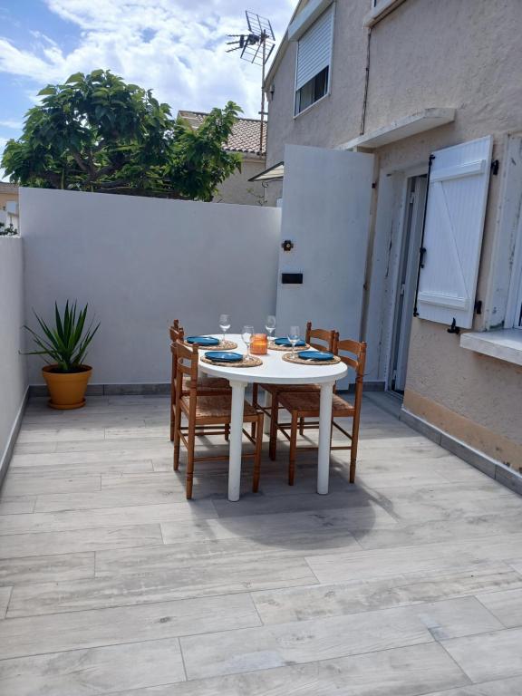 une table blanche et des chaises sur une terrasse dans l'établissement Gîte les Rougets, à Narbonne