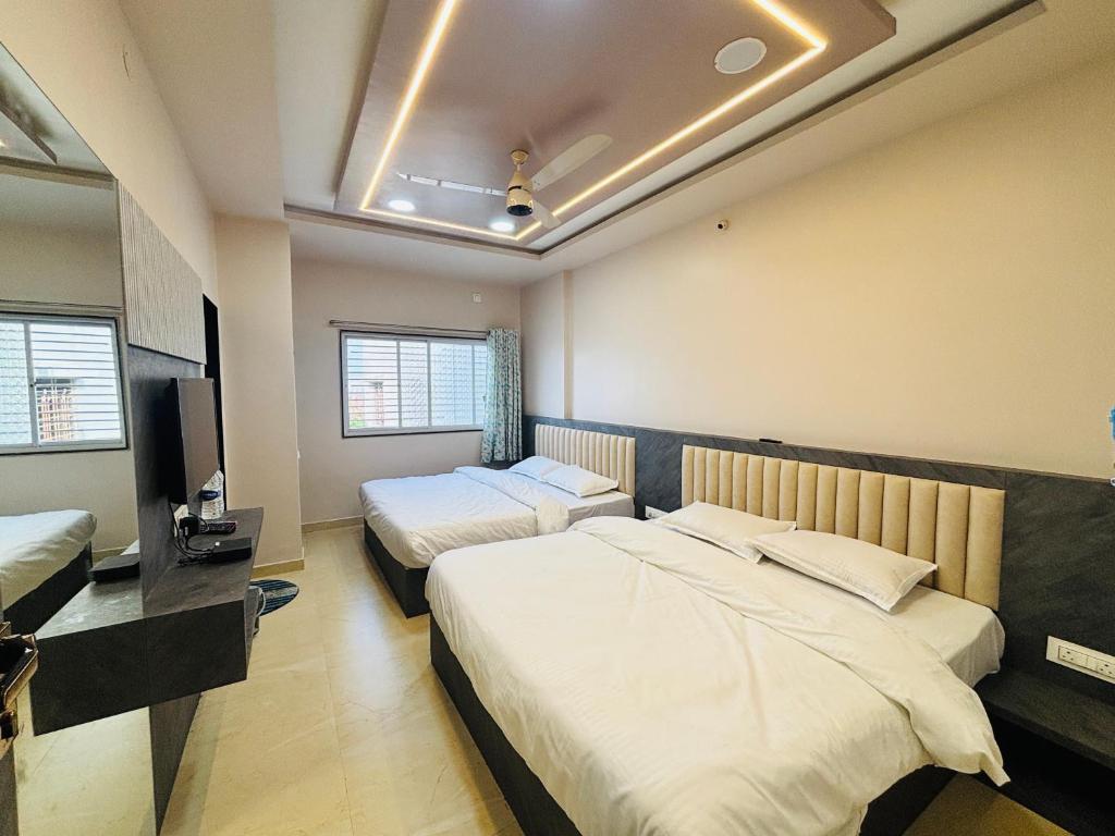 una camera d'albergo con due letti e una televisione di Chhatrachhaya Bhakt Niwas a Tuljapur