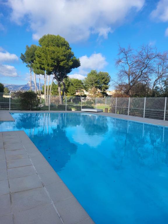 une piscine bleue avec des arbres en arrière-plan dans l'établissement Maison entre mer et montagnes, à La Gaude