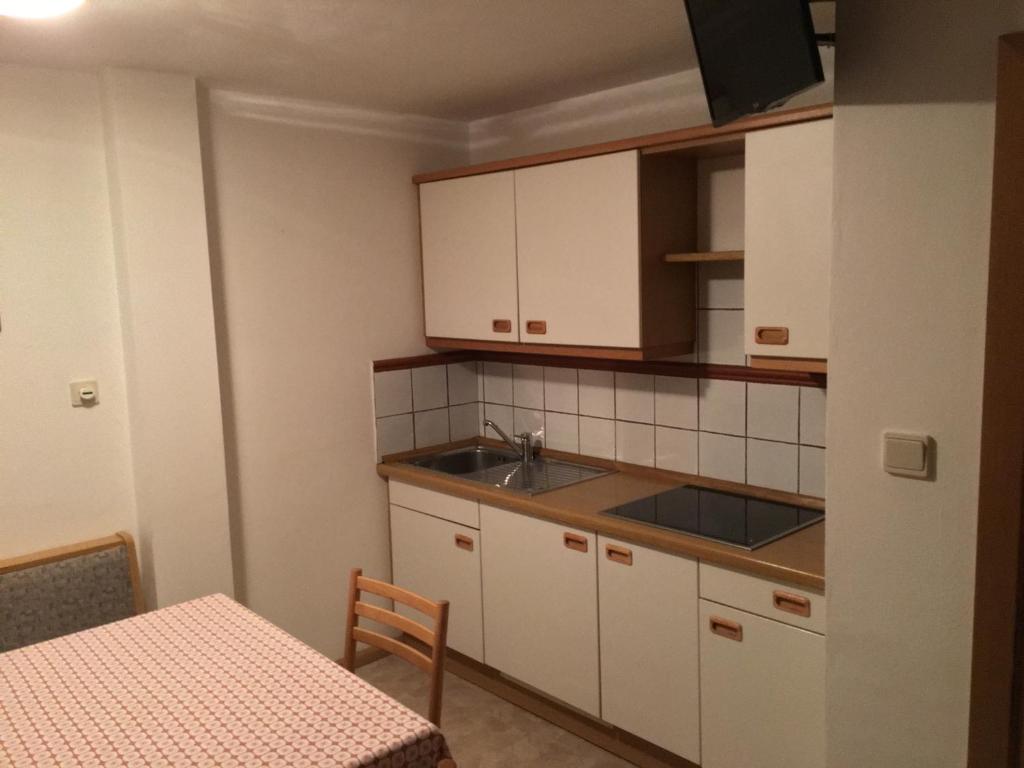 a kitchen with white cabinets and a sink and a table at Fallerhof in Villnoss