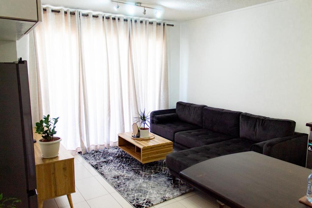 a living room with a black leather couch in front of a window at Serenity Escape Windhoek in Windhoek