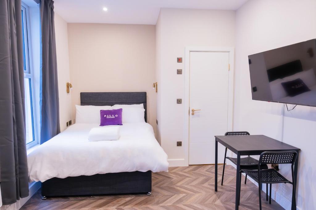 ロンドンにあるPillo Rooms Apartments - Chelseaのベッドとテーブルとテレビのある寝室