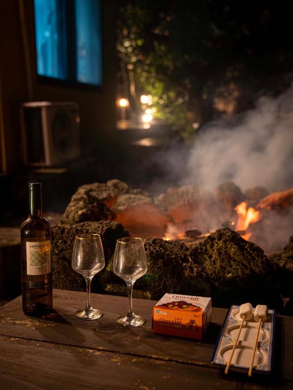 a bottle of wine and two wine glasses next to a fire at Jeju Love Stay Yellow in Jeju
