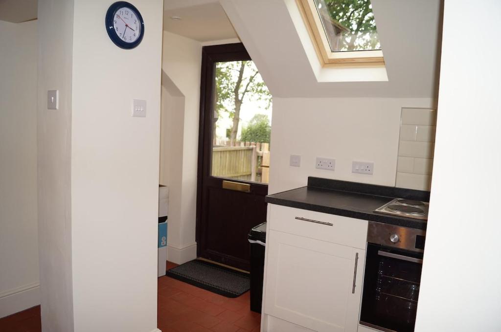 a kitchen with a clock on the wall next to a door at 2 Buckatree Cottage in Wellington