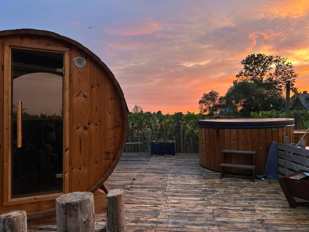 a wooden barrel sitting on a patio with a hot tub at Wellness B&B Meijdema in Ternaard