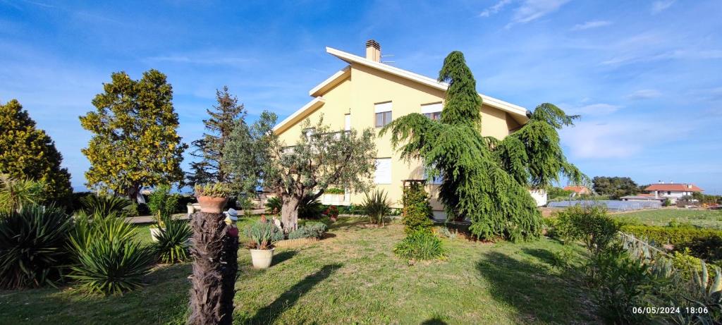 a yellow house with trees and plants in the yard at Casa vacanze Mare Monti in Grottammare