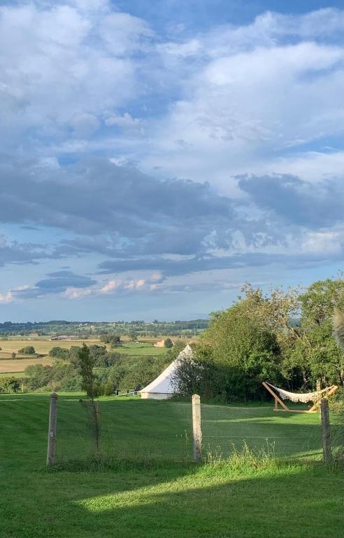 un champ avec une clôture et une tente blanche dans l'établissement Les Fresses Glamping, à Saint-Julien-la-Genète