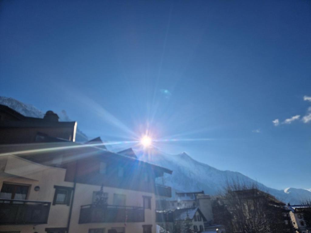 un soleil brillant sur un bâtiment avec des montagnes en arrière-plan dans l'établissement La Ginabelle 2 - Vue MontBlanc, à Chamonix-Mont-Blanc
