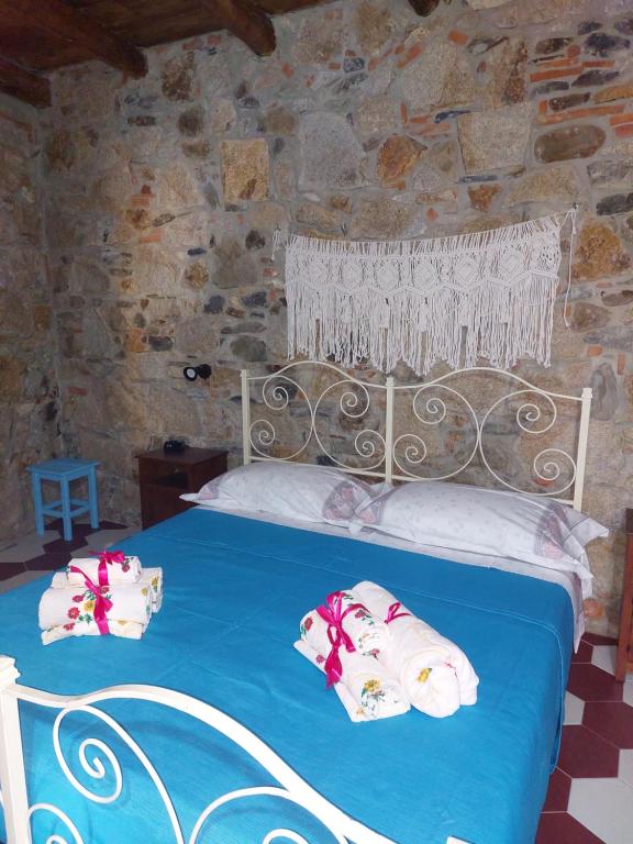a bedroom with a bed in a stone wall at Su Furriadroxiu in San Vito