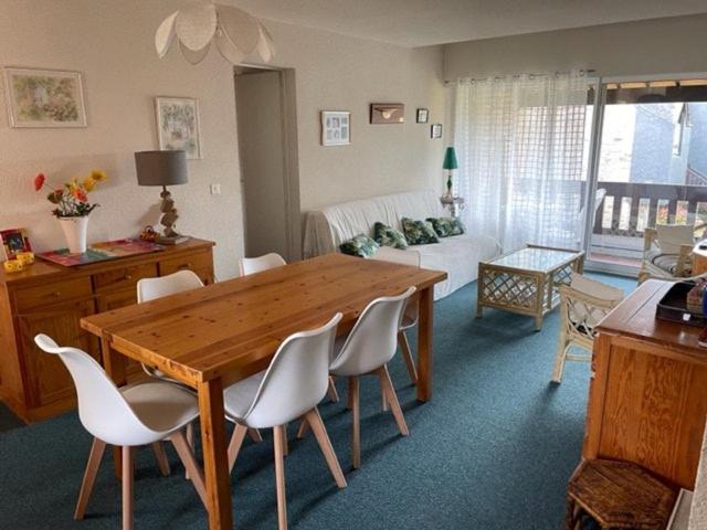 un salon avec une table en bois et des chaises blanches dans l'établissement TY DANY appartement 150m de la plage, à Carnac