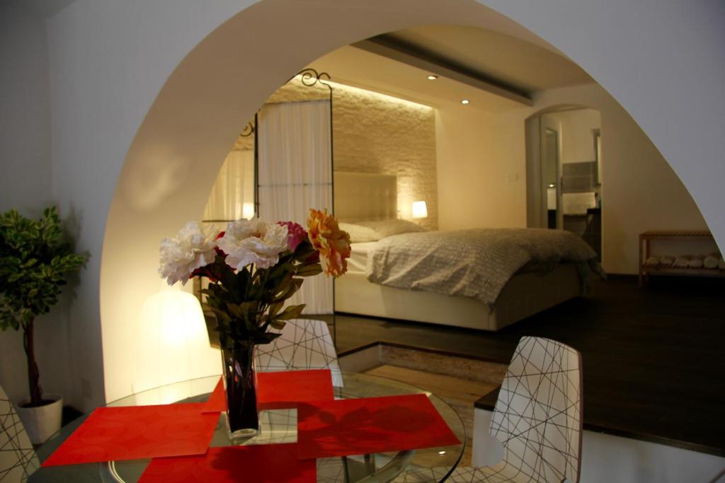 a vase of flowers on a glass table in a bedroom at Katana Apartments in Catania