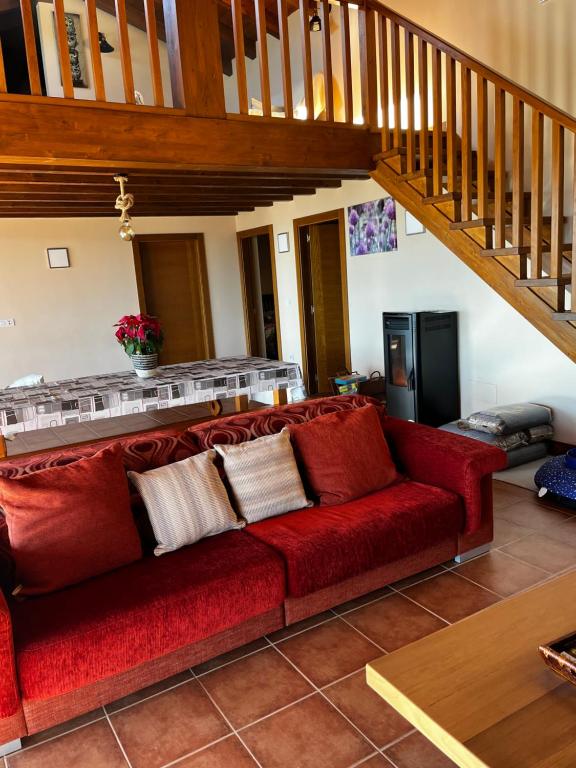 czerwona kanapa w salonie ze schodami w obiekcie Lobetios - Casa rural w mieście Parada de Achas
